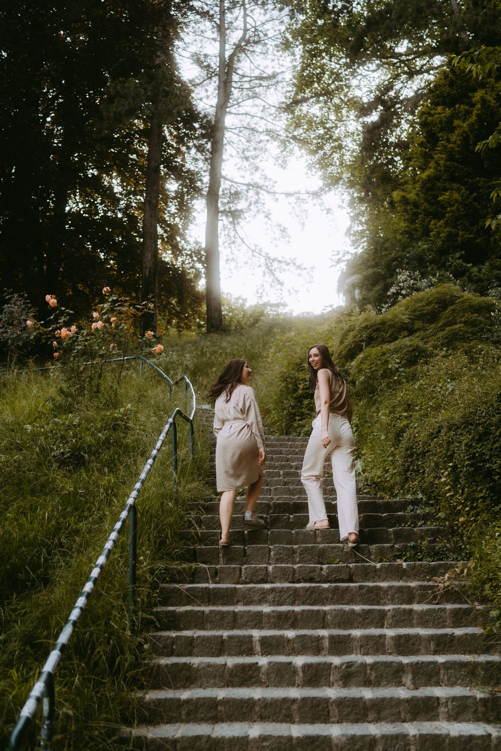 Friends ascending rustic stone steps in a serene garden setting.