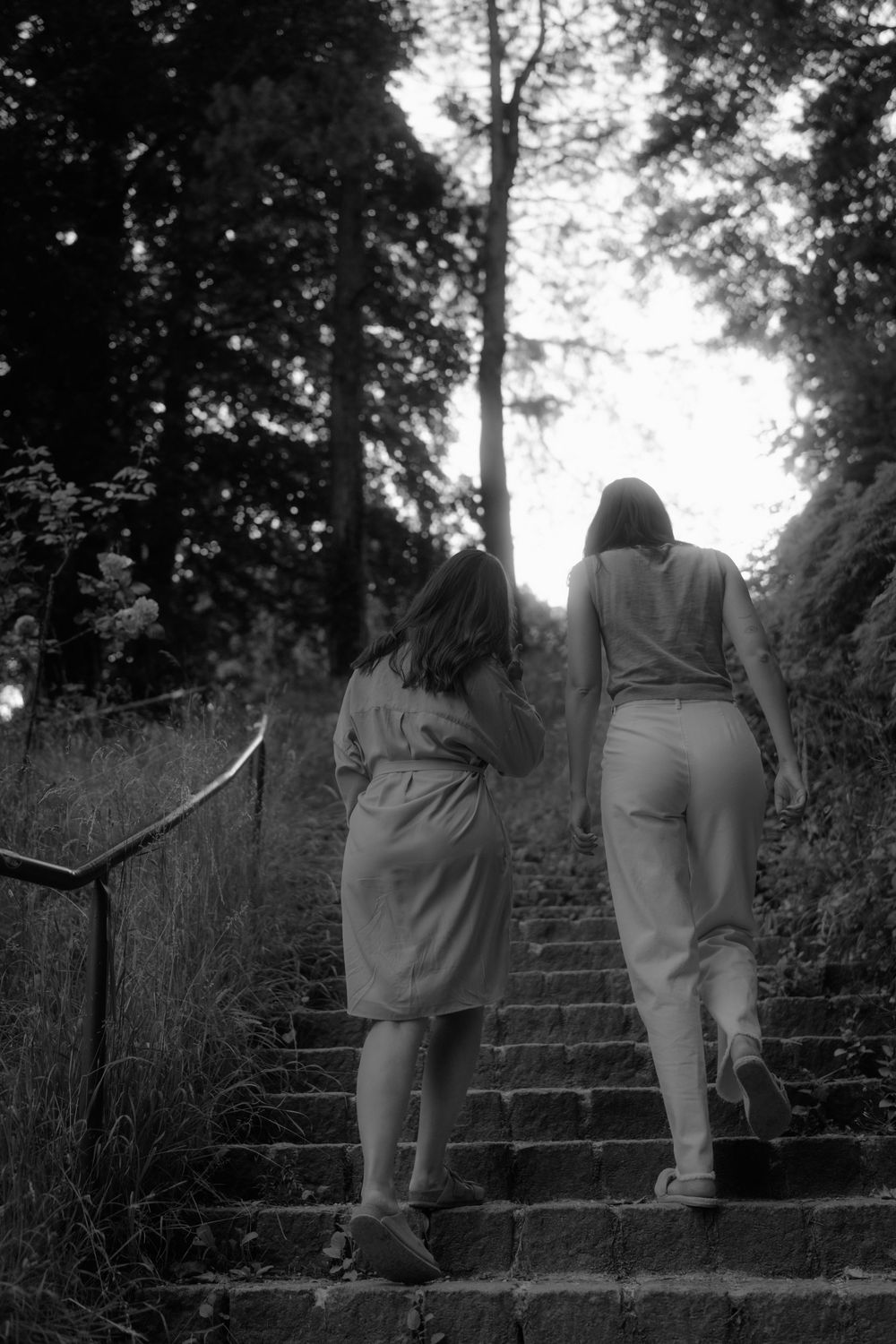 Black and white image of friends walking up stone garden steps together.