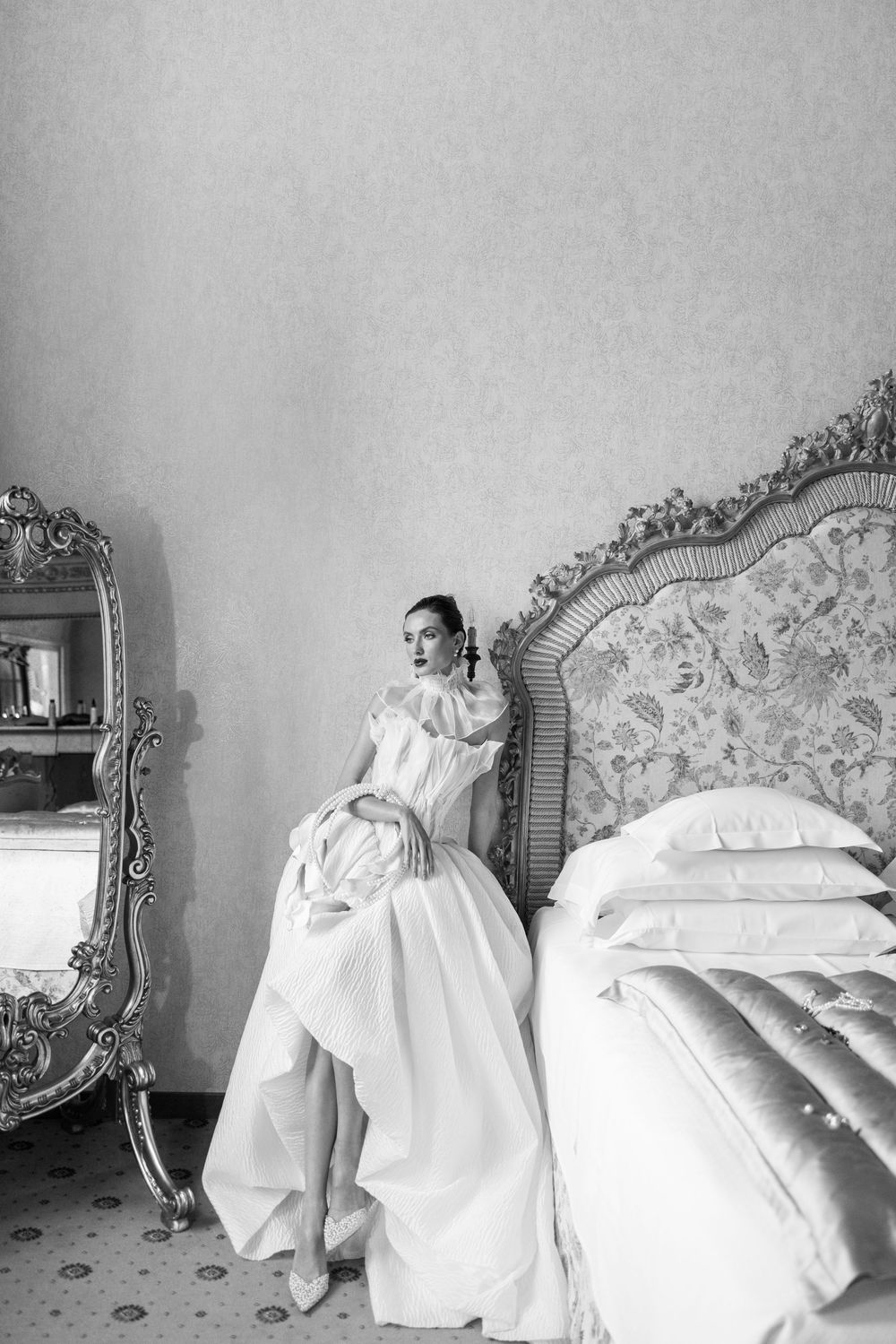 A sequence of black and white photographs showing a person reclining on an ornate vintage bed with white linens.