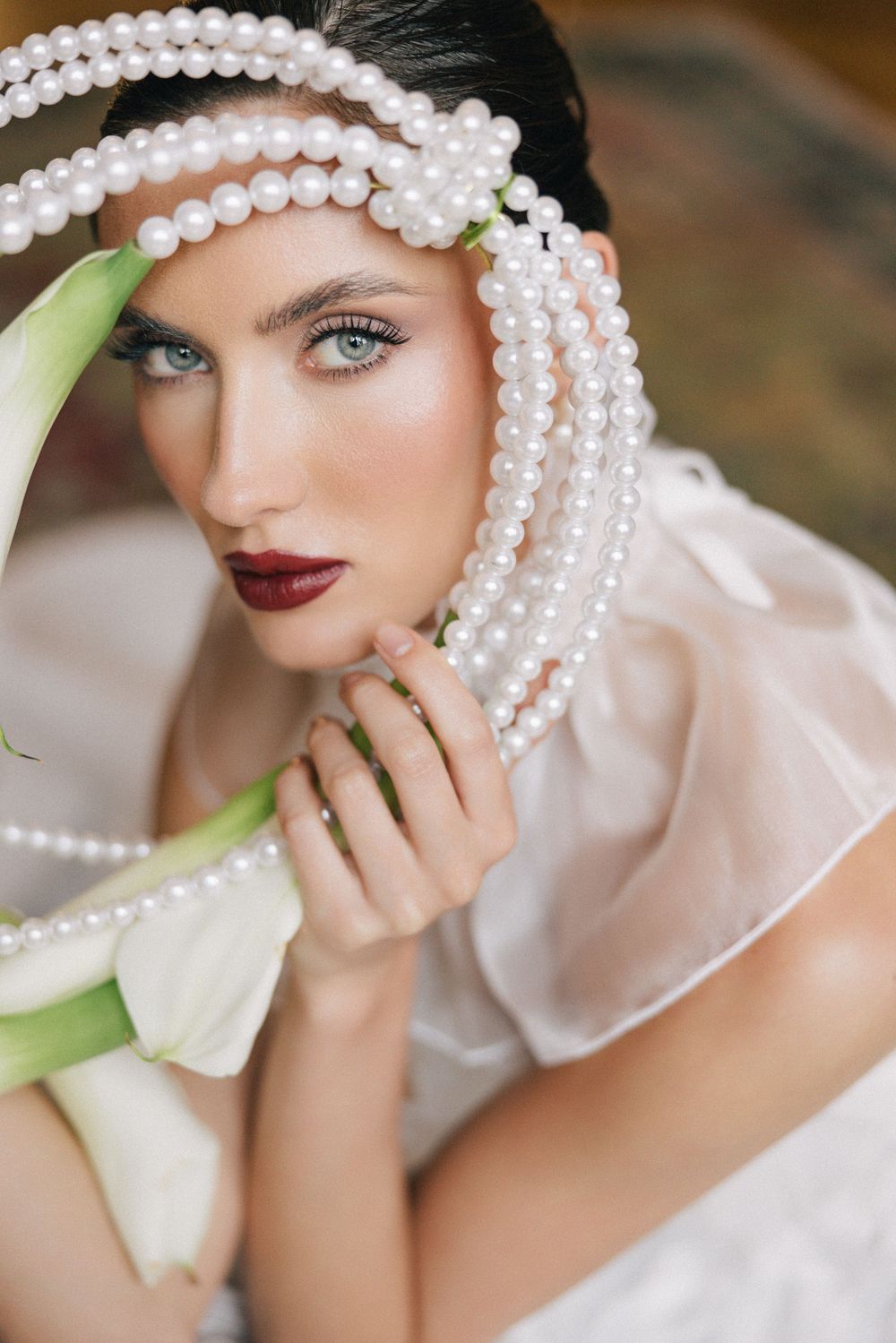 Elegant bridal portrait featuring pearl hair accessories, white calla lilies, and romantic soft lighting.