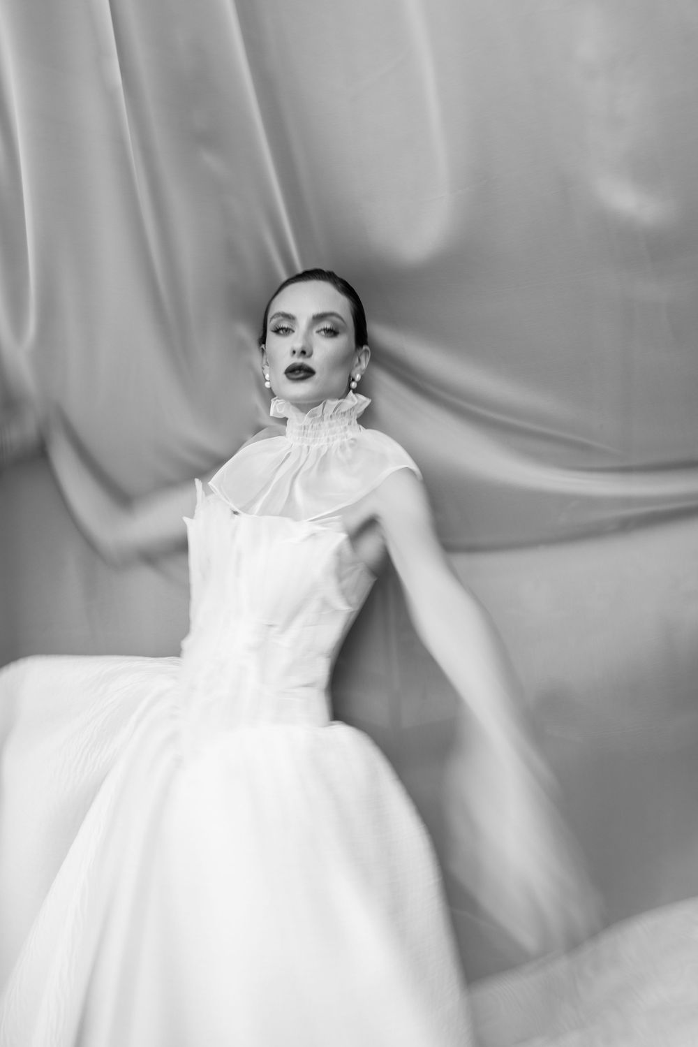 Dramatic black and white fashion portraits featuring white dress against soft backdrop.