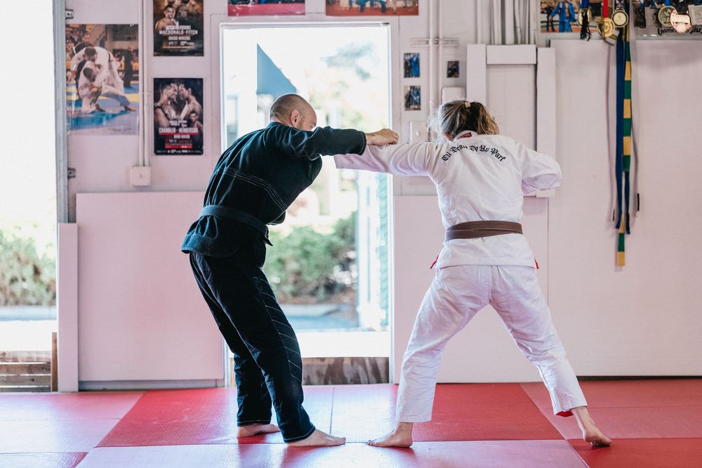 Students practice martial arts moves on red mats in a training studio with photos and decorations on the walls.