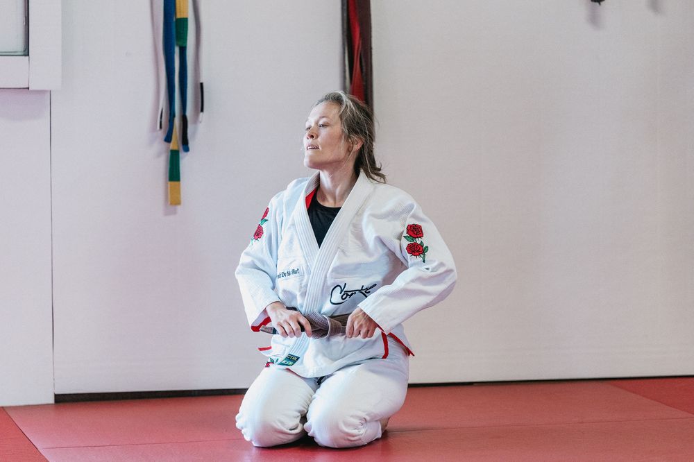 Students practice martial arts moves on a red mat floor in a bright training studio.