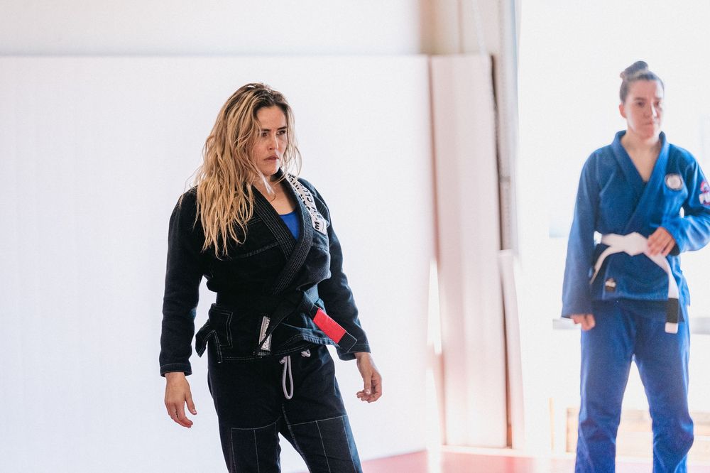 A group of dancers in blue and black outfits practicing choreography in a bright studio space.