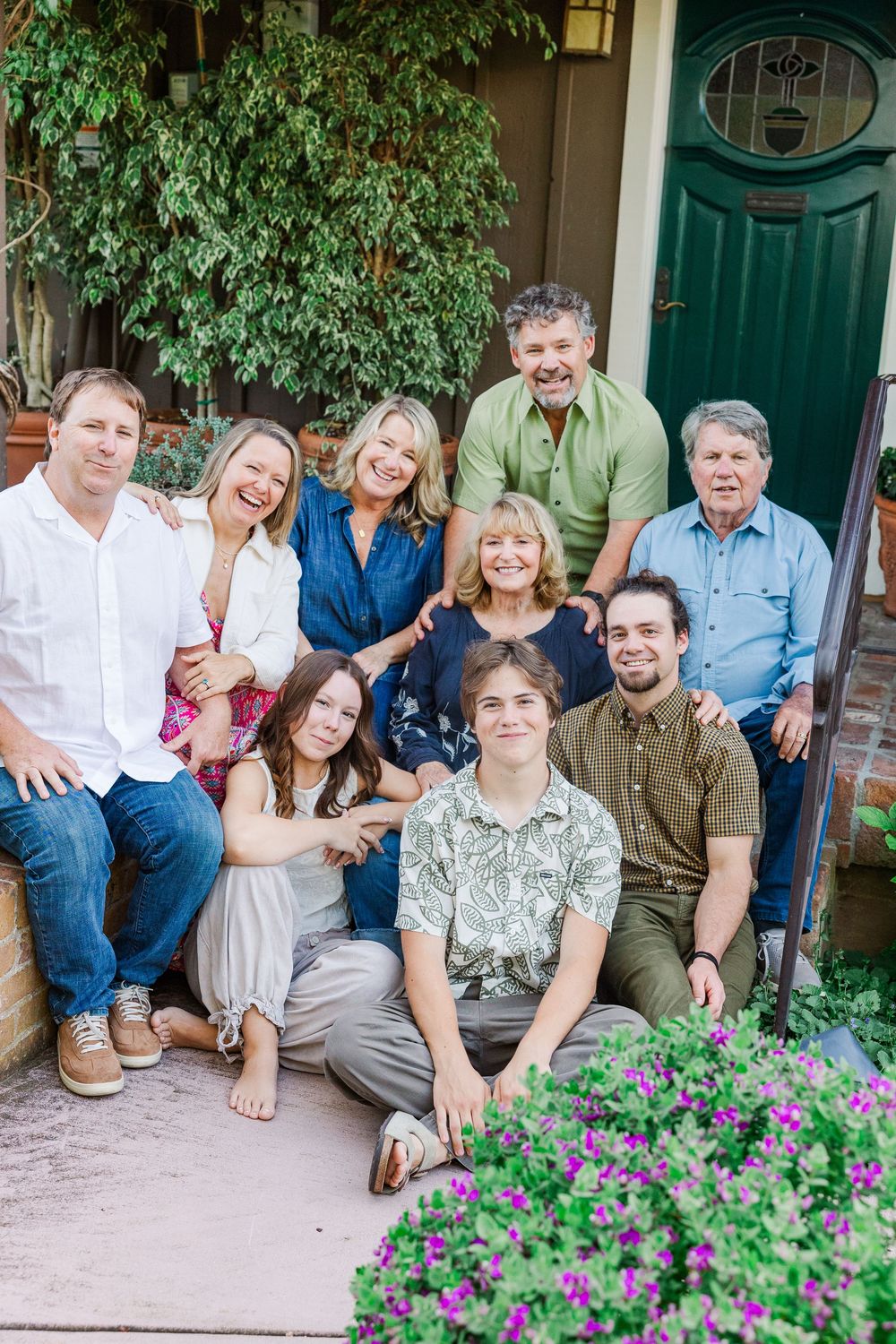 A group of people sitting together on outdoor steps with purple flowers in the foreground.