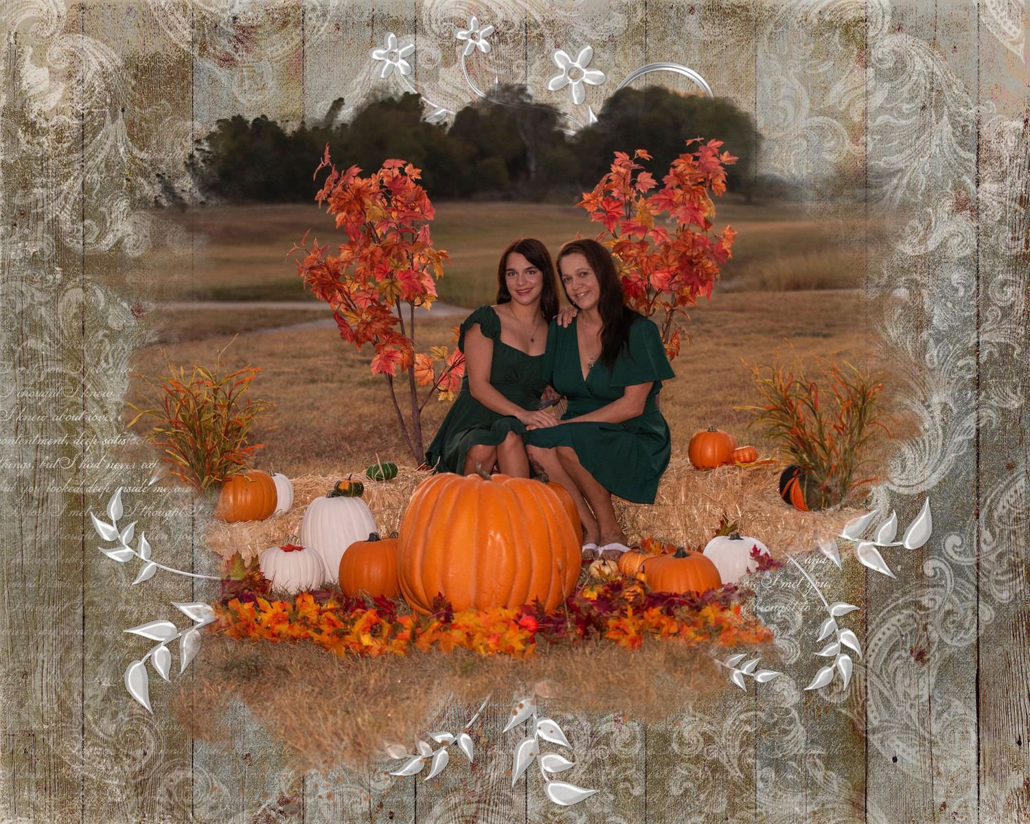 Two people in black dresses pose with autumn decorations and large orange pumpkins in a rustic outdoor setting.