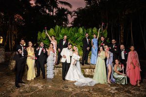 A group of people in formal attire stand together outdoors at dusk during a wedding celebration.