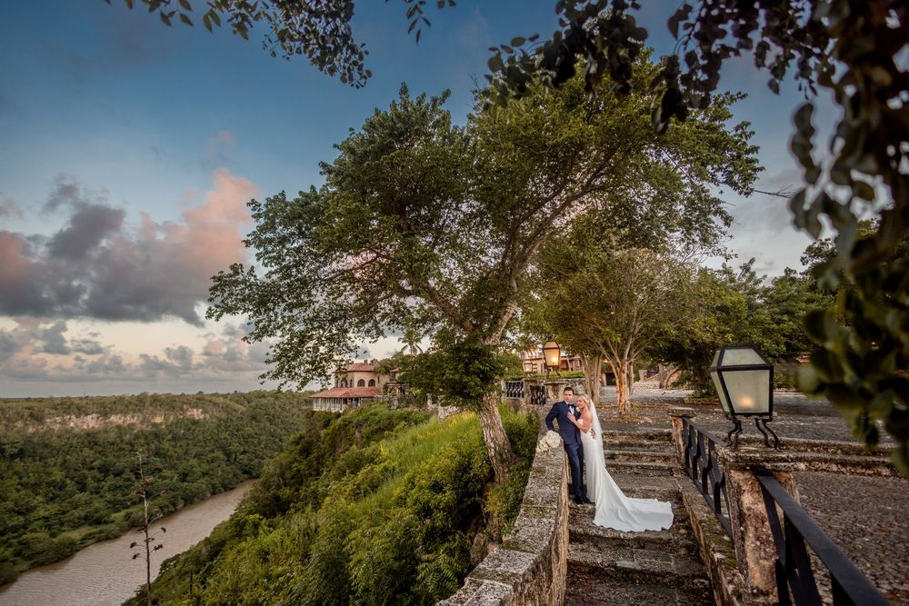 Scenic coastal boardwalk with wooden railings extends along the shoreline as clouds drift across the blue sky at sunset. Altos de Chavon
