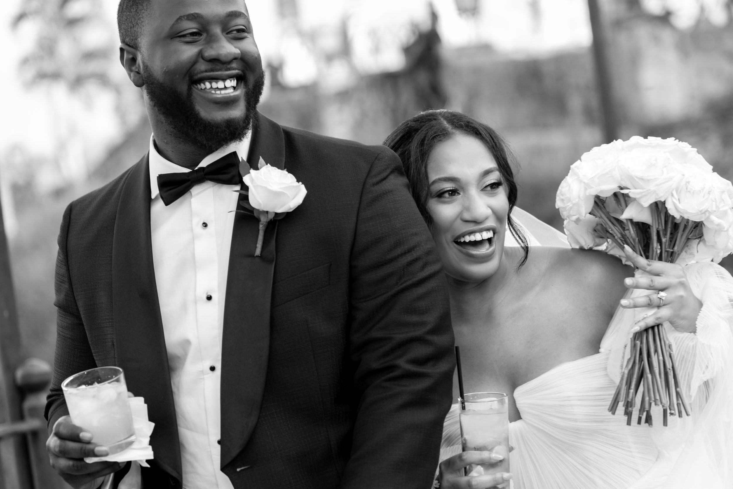 Black and white photo of a joyful bride and groom laughing together on their wedding day.
