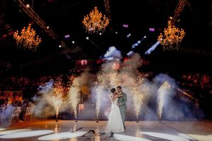 Figure skaters perform in an ice show under glowing golden chandeliers and theatrical smoke effects.