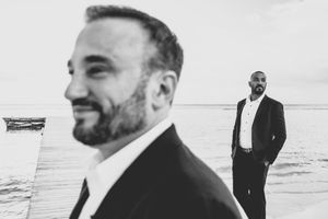 A series of black and white beach photos showing a person in formal attire walking along the shoreline at sunset. Juanillo Beach Cap Cana