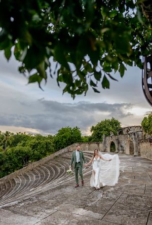 Wedding couple poses on ancient stone amphitheater steps against dramatic stormy sky at historic ruins.