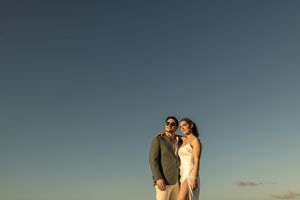 Couple embraces on a beach during golden hour with the ocean and dramatic sky in the background. Punta Cana