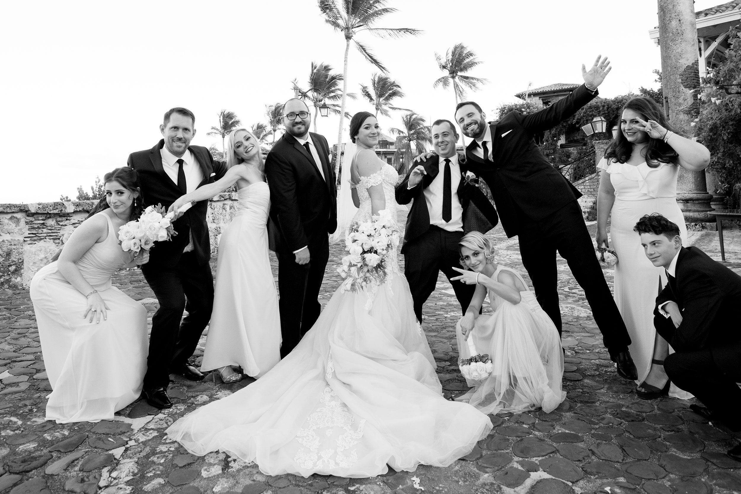 Wedding party poses for dynamic group photos on a tropical beach.