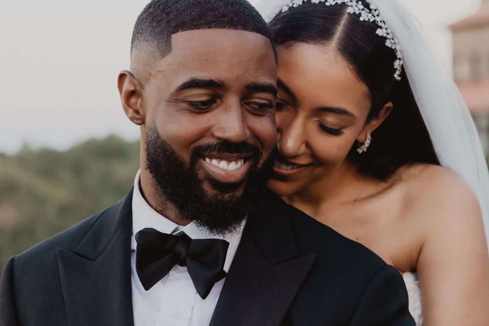 A joyful newlywed couple share an intimate moment together during their outdoor wedding celebration.