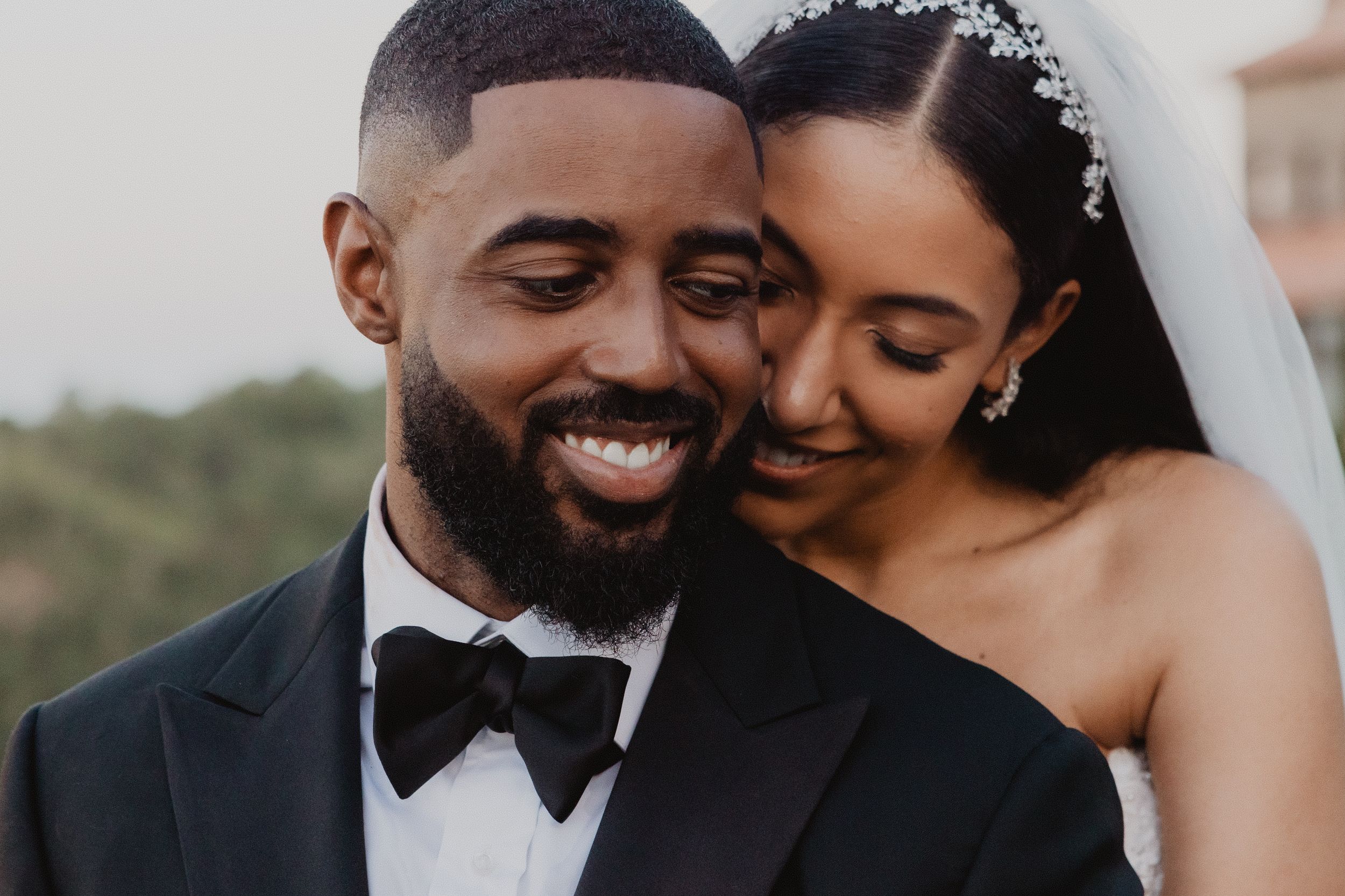 A joyful newlywed couple share an intimate moment together during their outdoor wedding celebration.