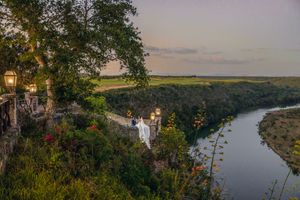 Scenic sunset view of a winding river valley with lush green forests and rolling hills stretching into the distance.