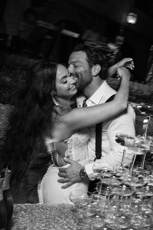 A romantic moment captured between a couple embracing above a champagne tower at their wedding celebration.