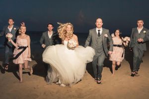 Wedding party jumps joyfully on the beach at sunset.