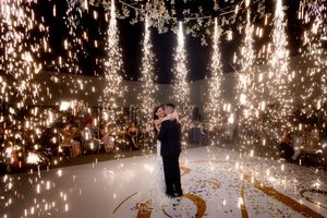 Sparklers create a magical light tunnel effect at an outdoor wedding celebration.