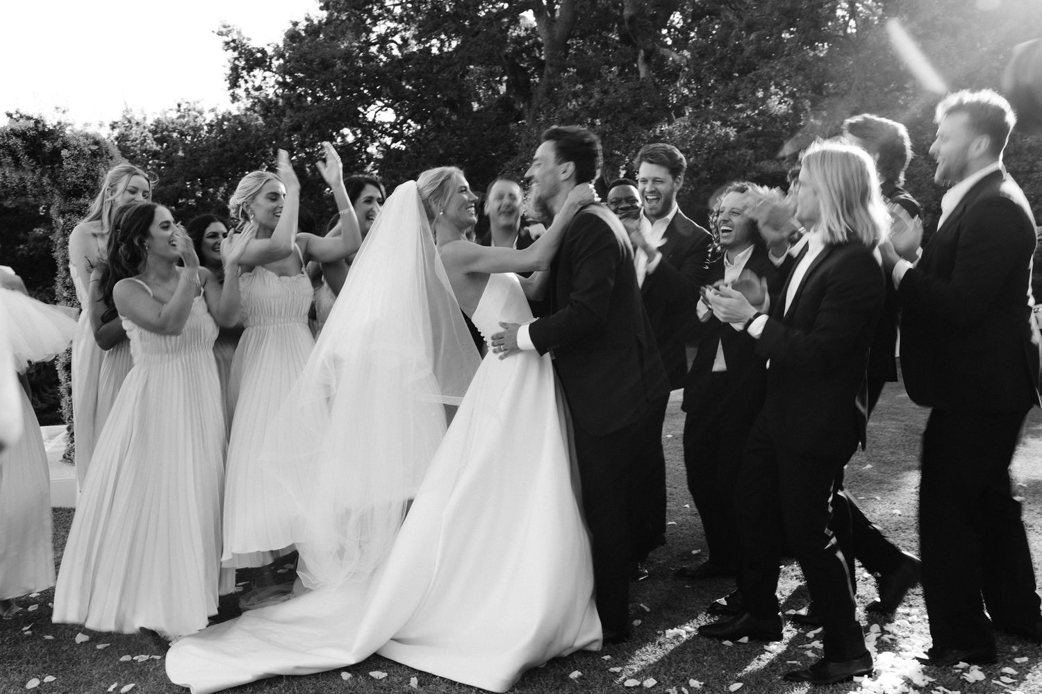 A black and white photo collage of a wedding party posing outdoors during a celebration.