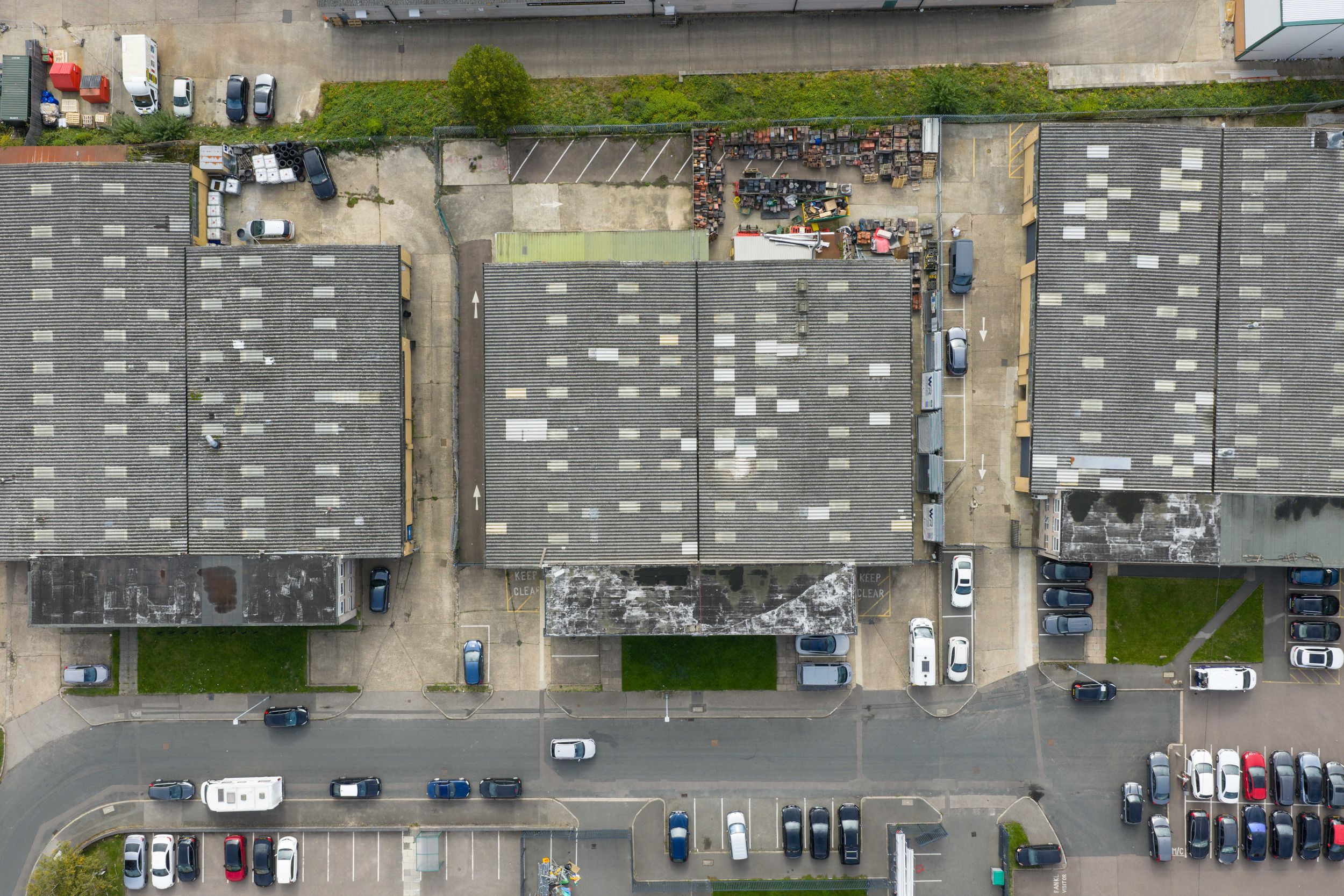 Aerial view of a large industrial warehouse complex with parked vehicles and storage units seen from above.