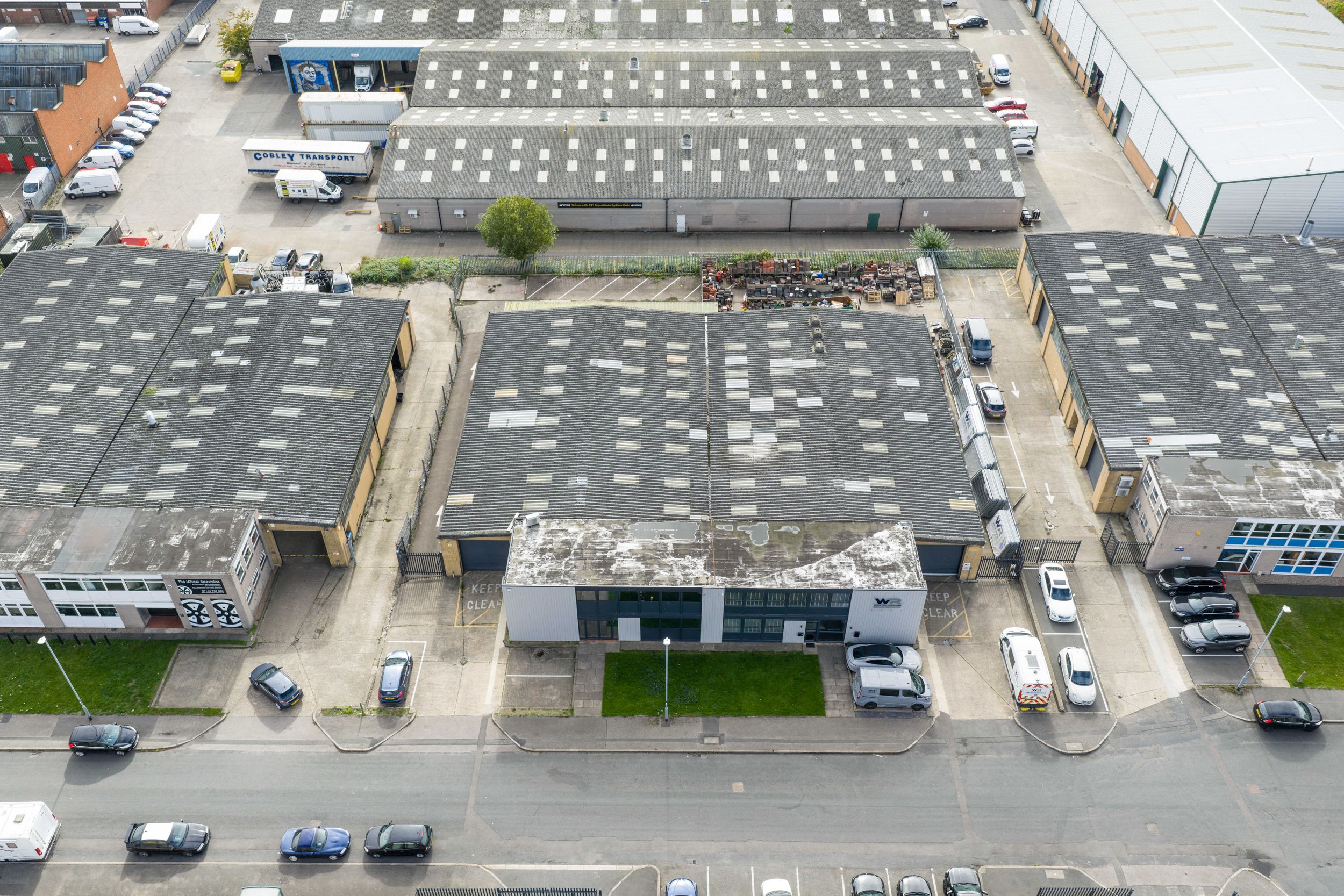 Aerial view of commercial buildings with flat roofs and parking lots in an industrial or retail complex.