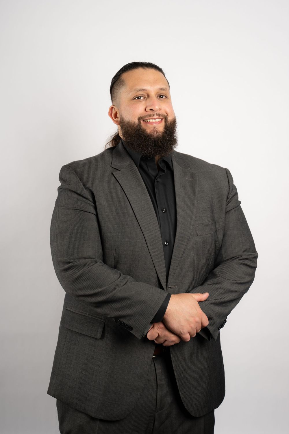 A person in formal attire smiles while posing against a white backdrop.