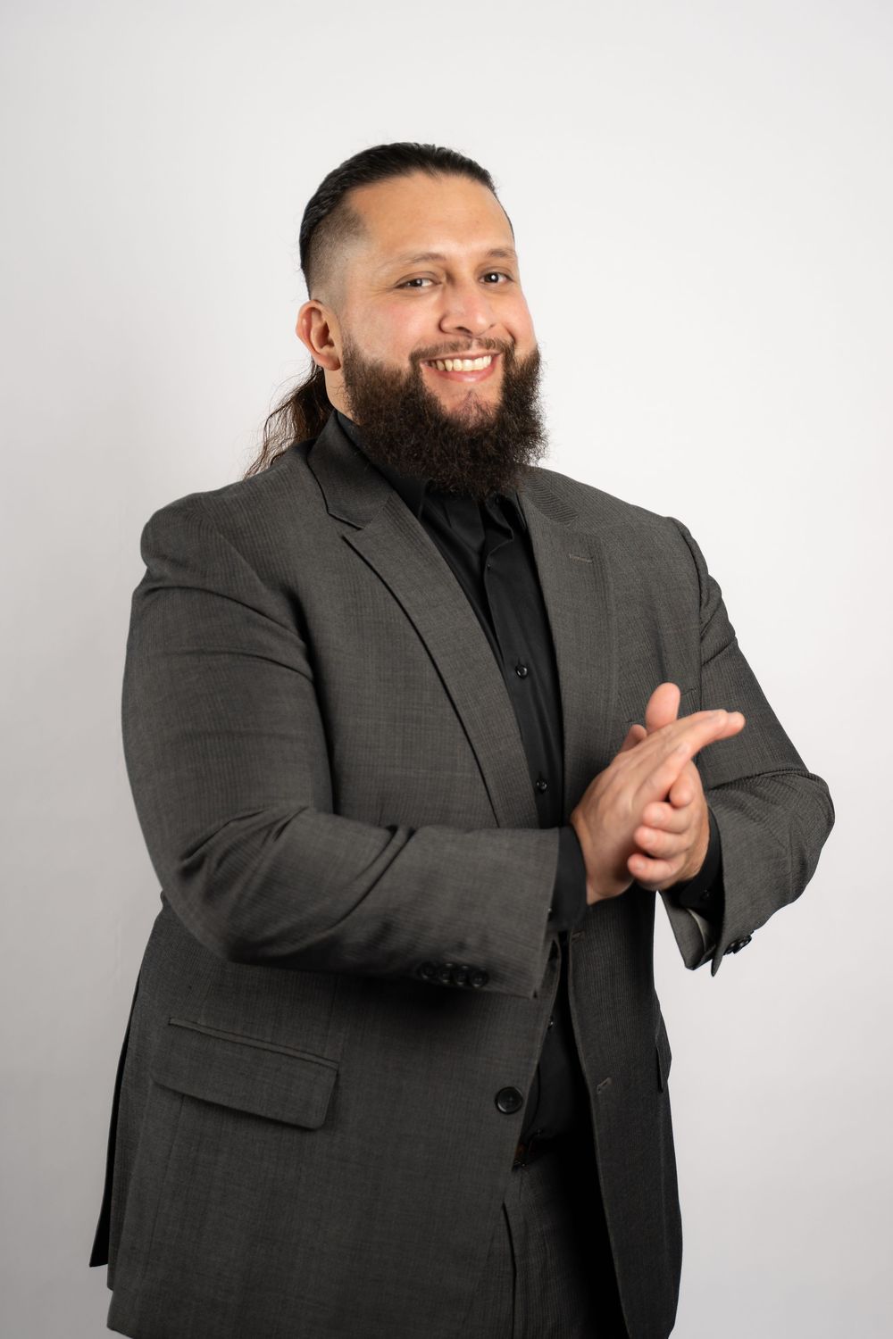 A person in a grey suit gestures expressively during a professional photoshoot.