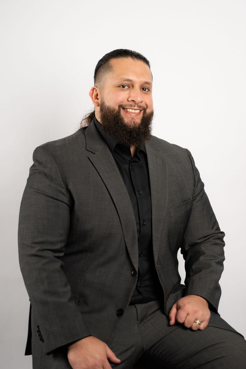 A person in business attire poses casually during a studio session.