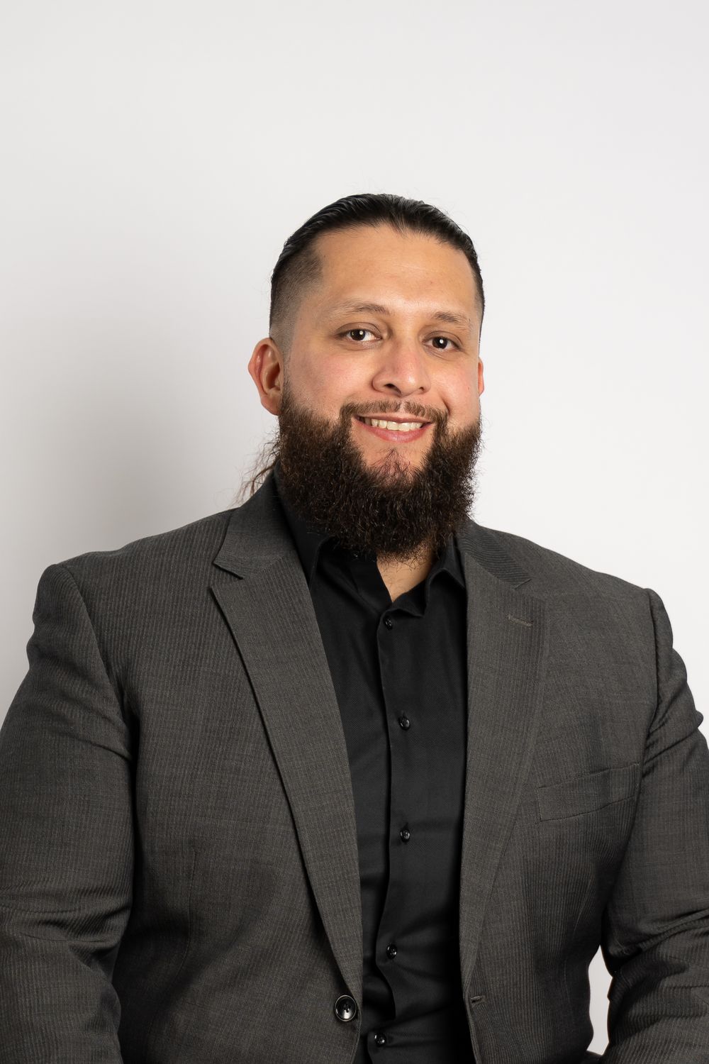 A person in a dark suit smiles warmly during a professional headshot session.