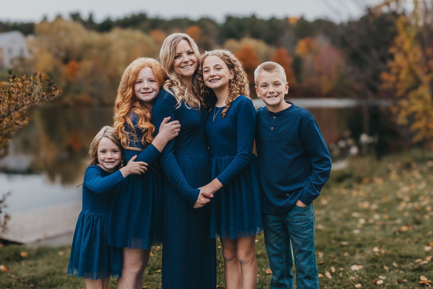 Group photo session on sandy beach during golden hour with coordinated blue and white outfits.