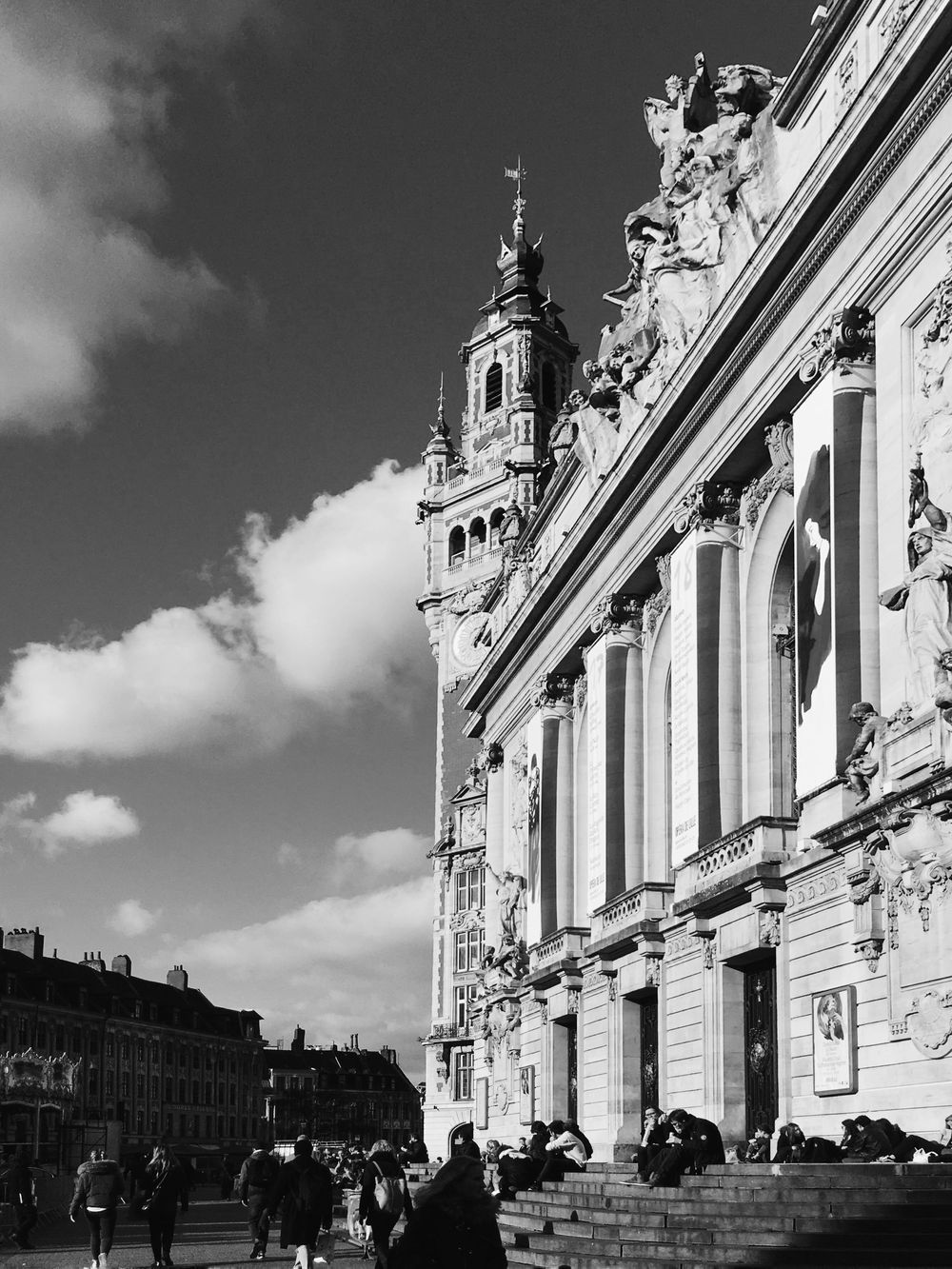 Black and white photo of an ornate Baroque building facade with a tall bell tower under cloudy skies.