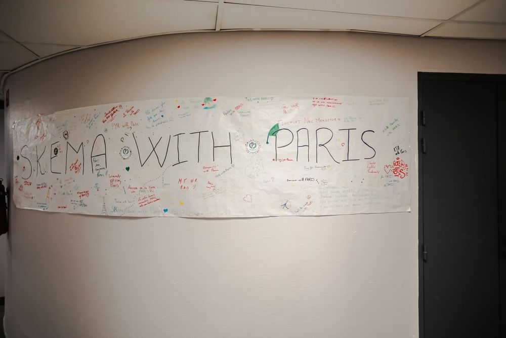Hand-written banner reading SKEMA With Paris displayed on a white wall with colorful signatures.