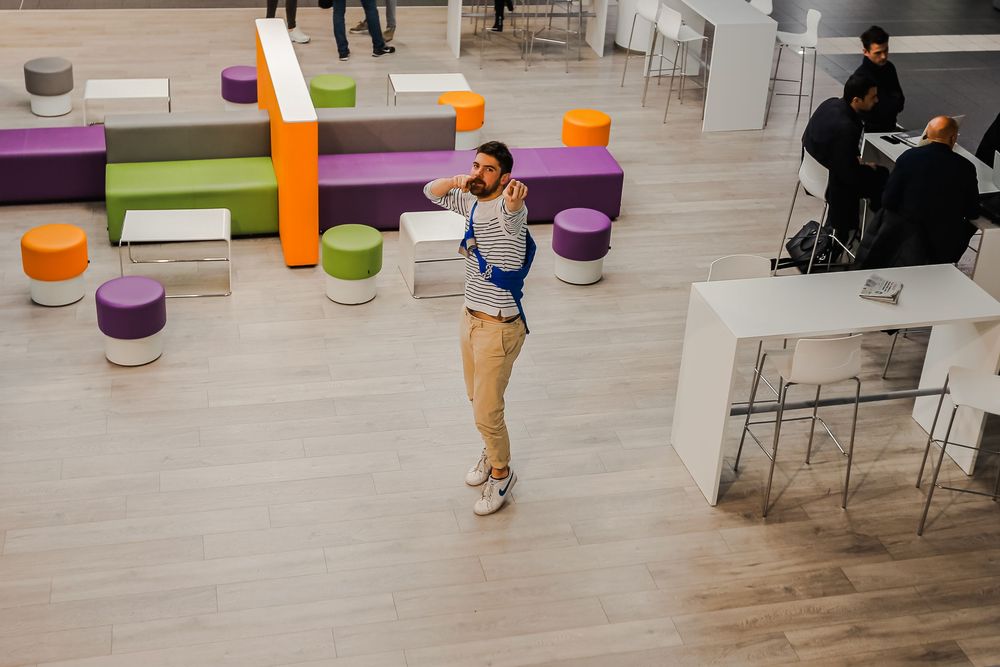 Student standing in a colorful open-plan lounge area with vibrant modular seating at SKEMA campus.