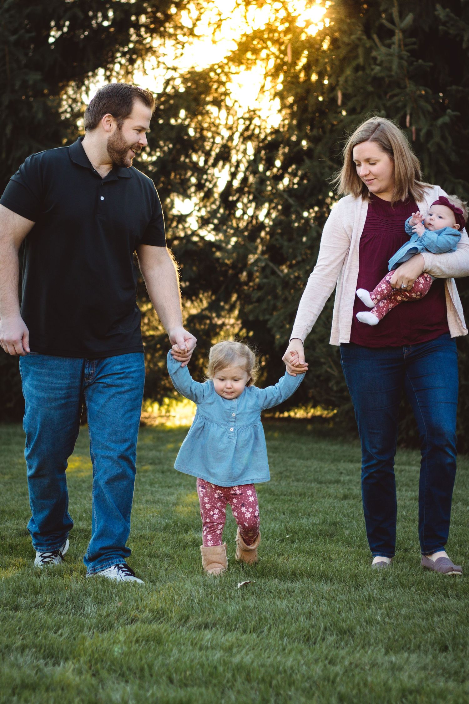 Family walking together in the grass at sunset, holding hands with toddler, Metro Detroit family photography.