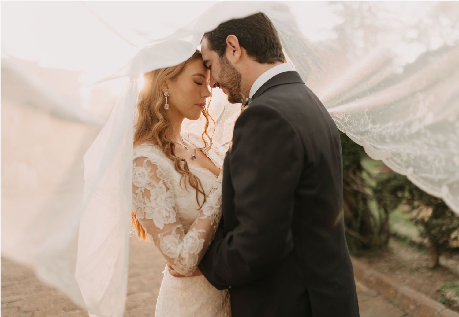 Intimate wedding moment photographed in warm desert lighting with flowing veil.
