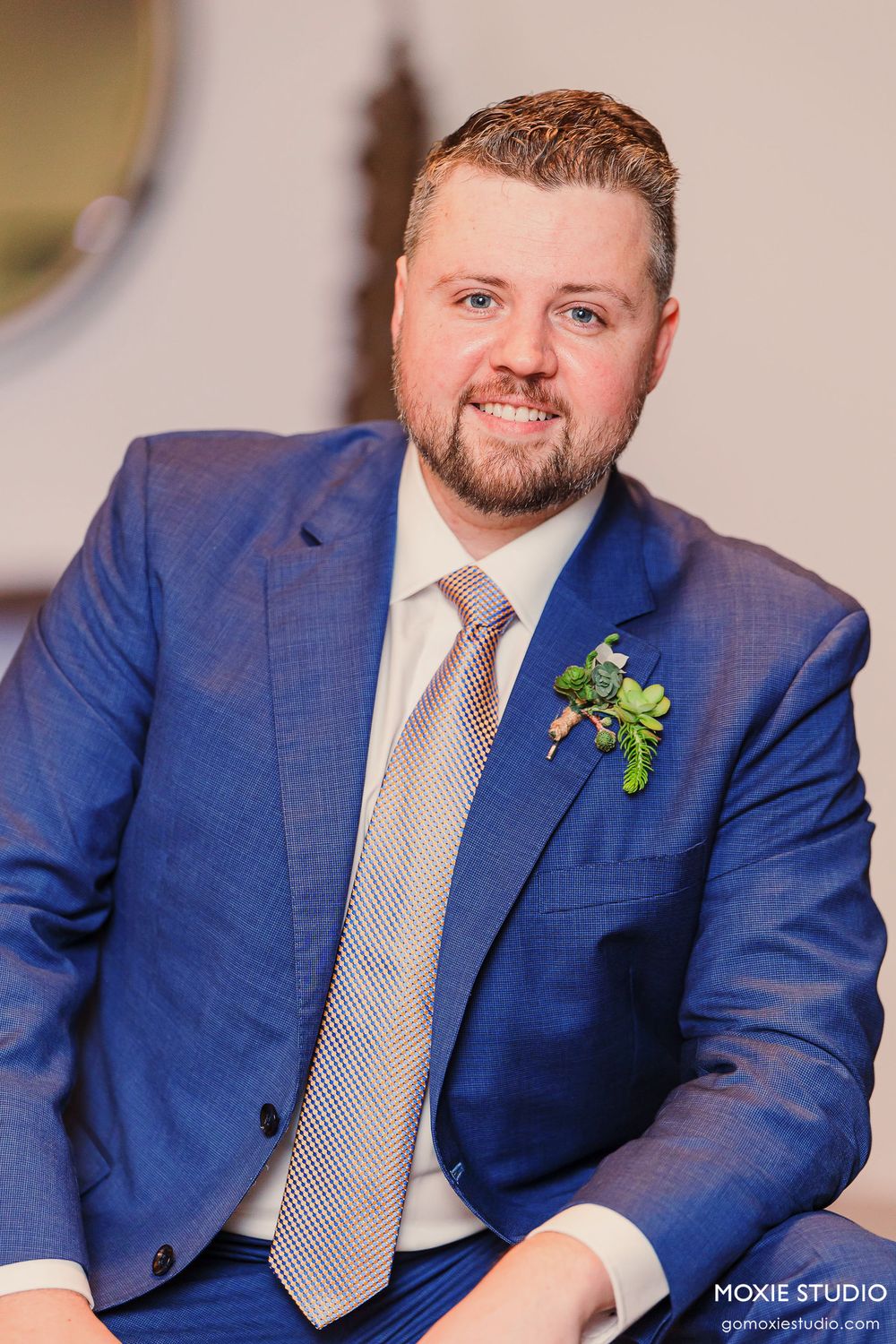 Professional portrait series showing a groom in a navy blue suit with a light gray tie and boutonniere.