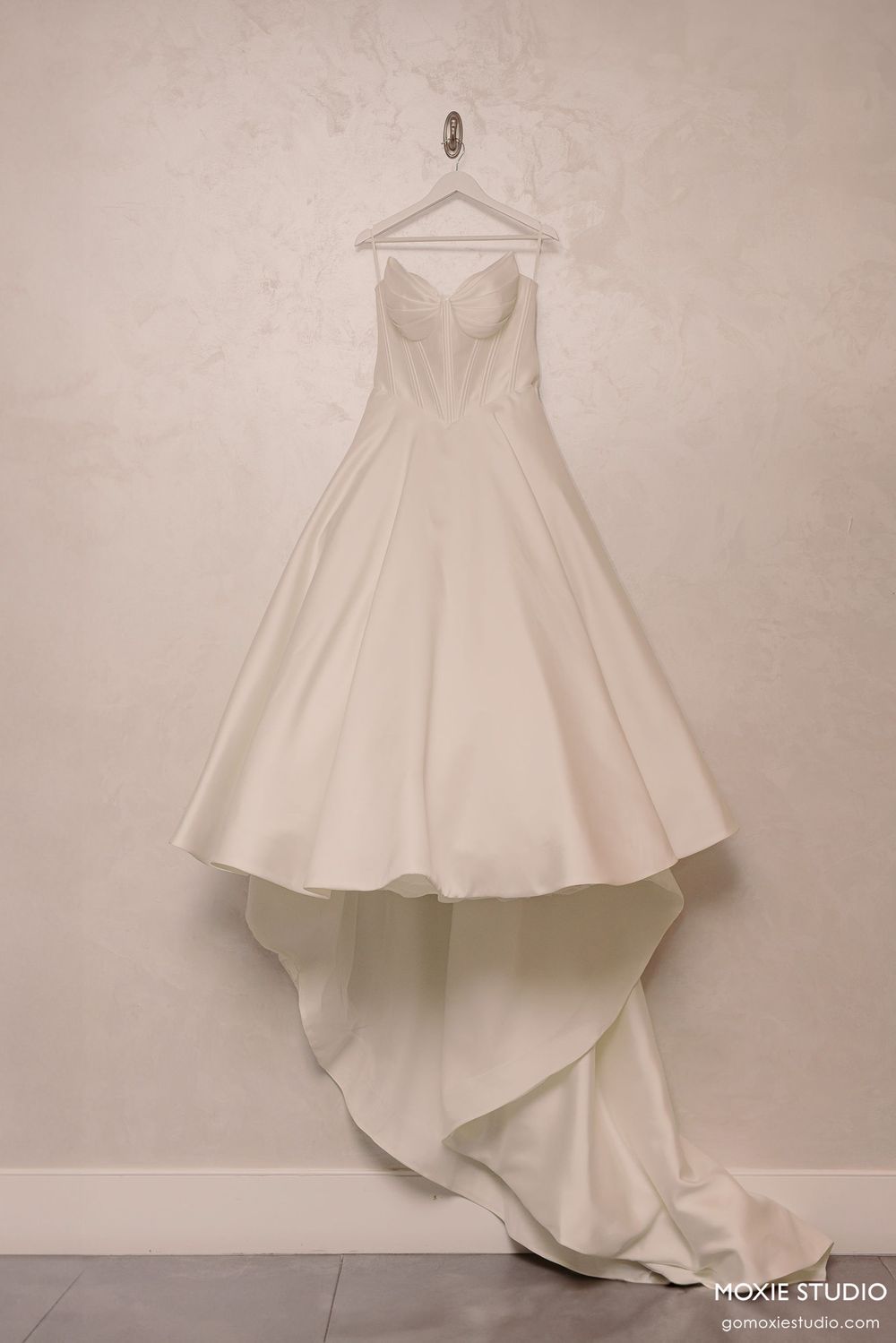 White wedding dress with flowing train photographed in sequence showing different angles and movement on beige background.