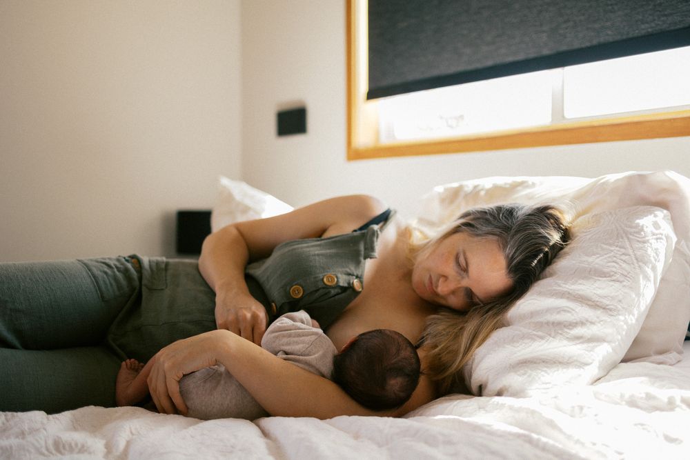 Someone rests peacefully in bed with soft morning light streaming through the window.