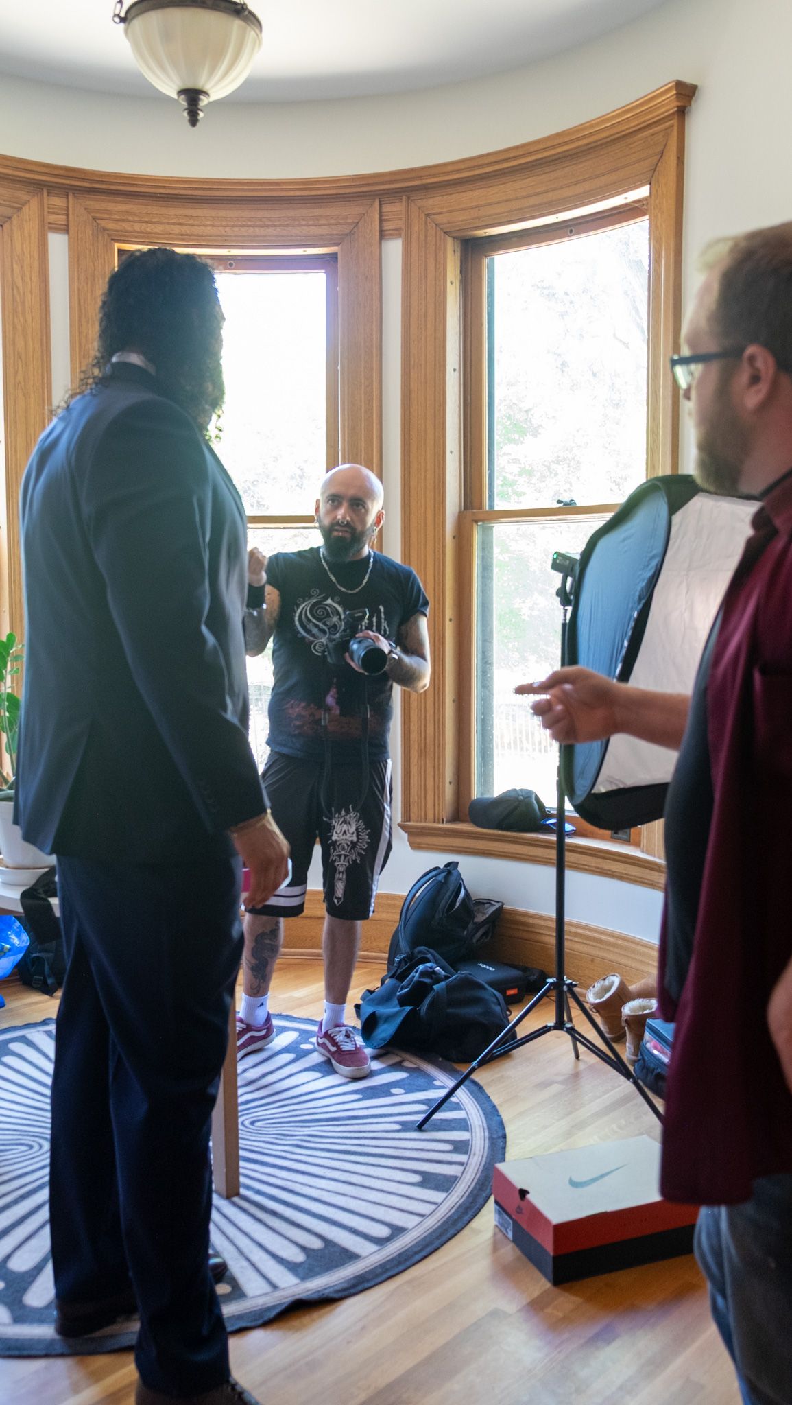 Group of people examining a curved bay window area with wood trim during what appears to be a home inspection.
