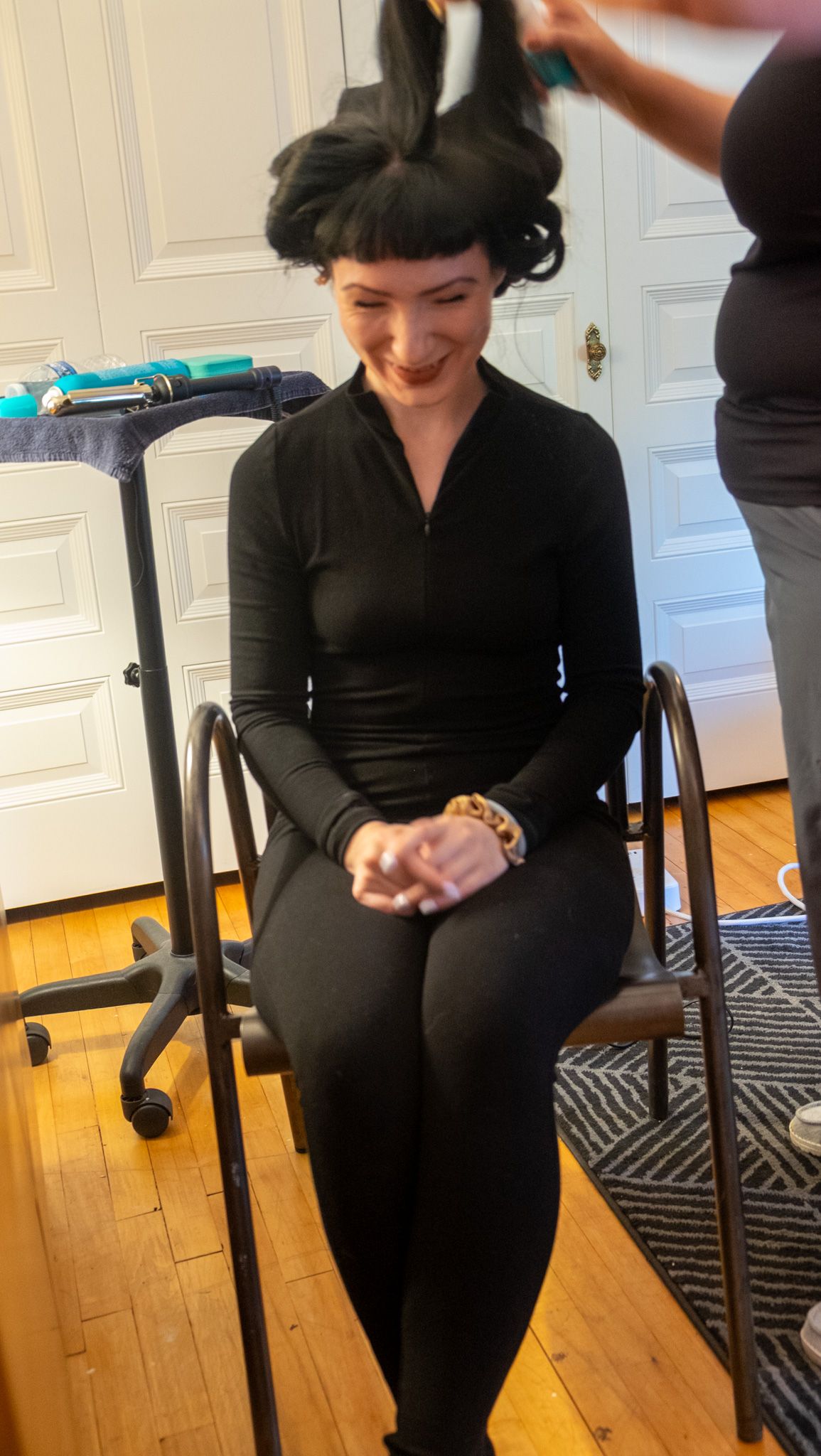 Person in black outfit sits on chair and performs arm movements during exercise sequence.