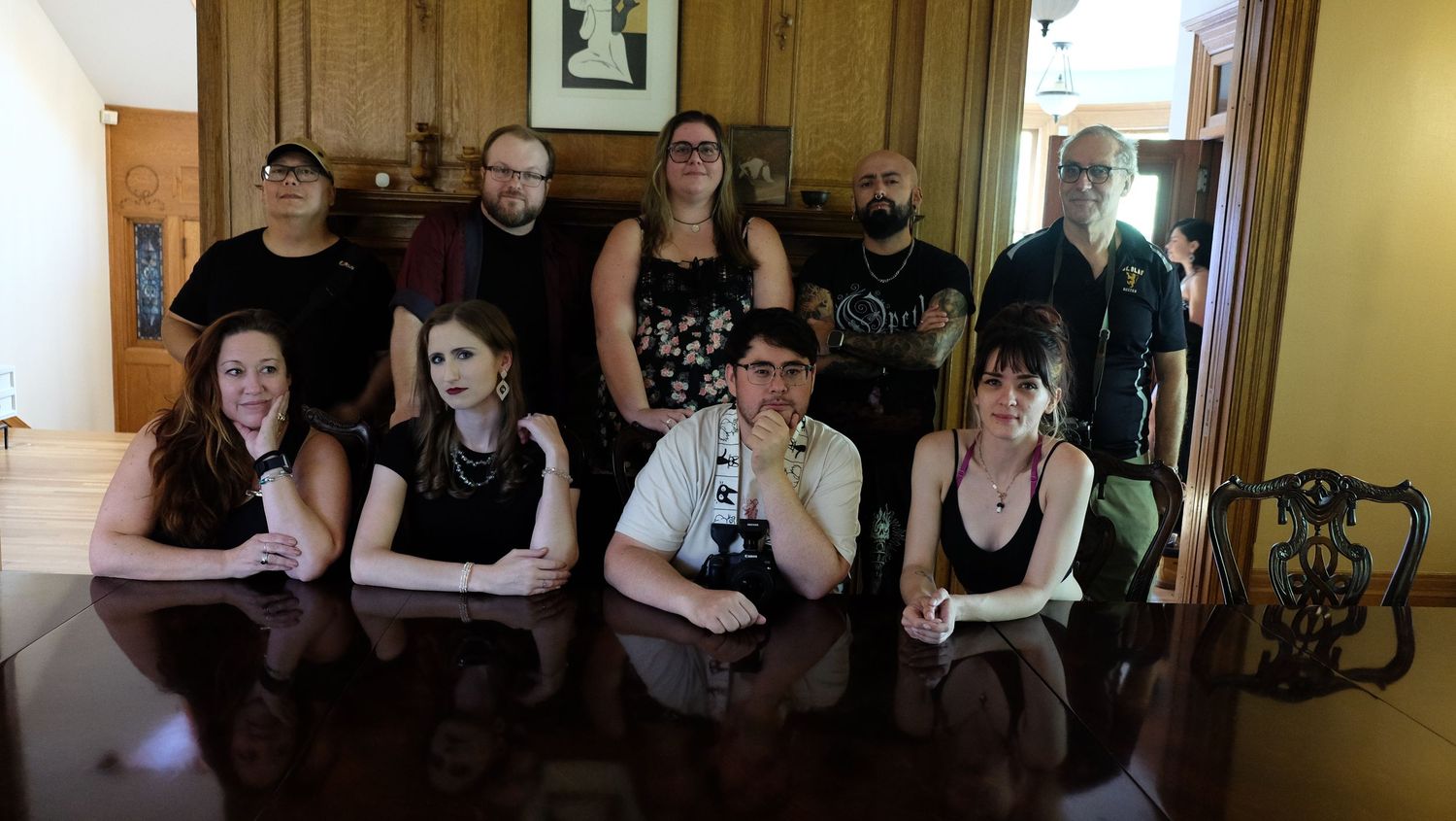 A group of people pose together in a row for a casual indoor photo.