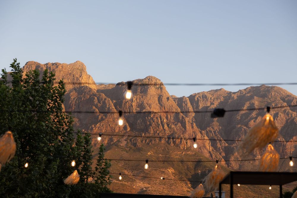 Scenic panoramic view of red rock cliffs at sunset with mountains in the background.