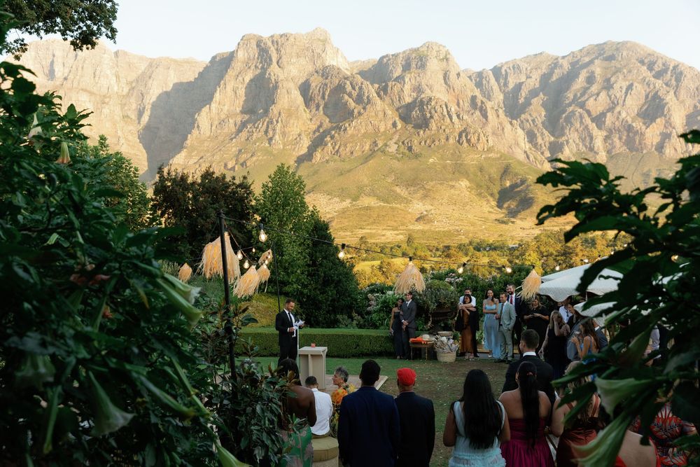 A group gathers outdoors against a backdrop of majestic mountain peaks during a scenic event.