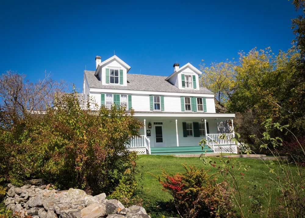 Panoramic view of white residential homes nestled on a green hillside under blue sky.