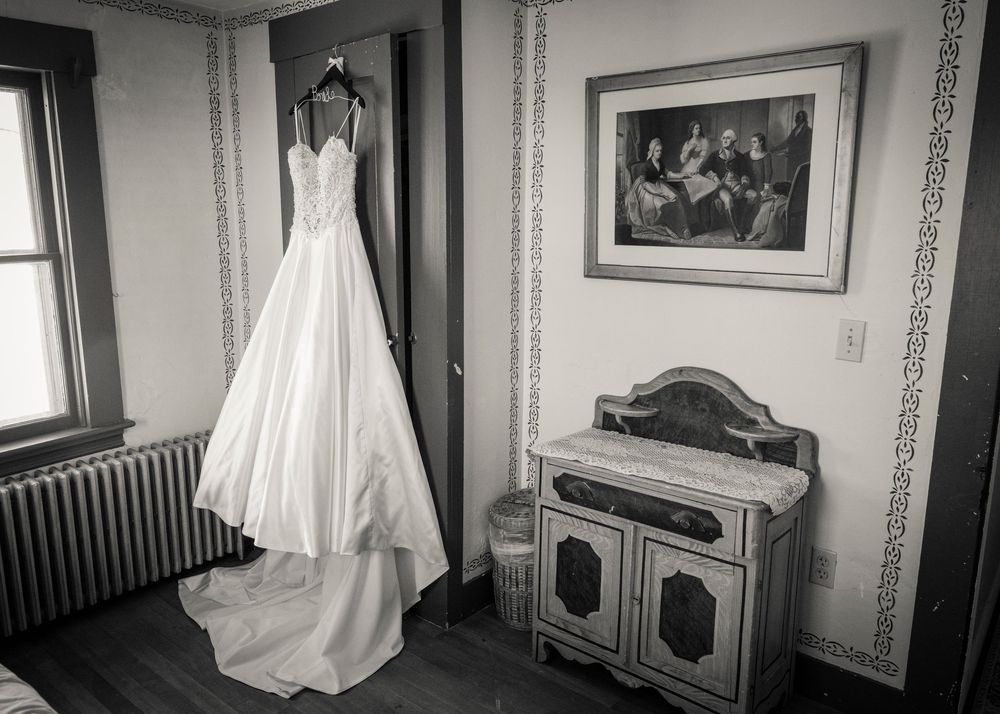 A black and white photo series showing an empty bedroom with a white wedding dress displayed in different angles and positions.