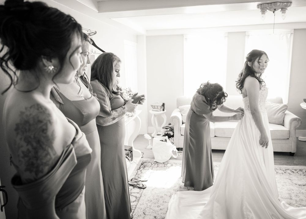 Black and white series of wedding preparation moments showing dress adjustments and final touches.
