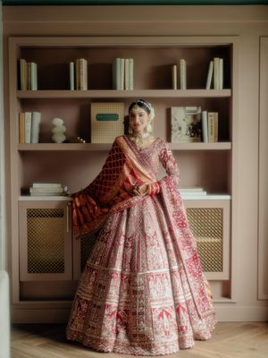 Ornate red and gold Indian bridal lehenga displayed in an elegant room with built-in shelving.