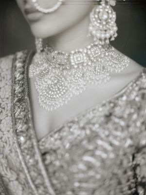Intricate beaded pearl neckline detail of a luxurious wedding dress with delicate embellishments and lace detailing.